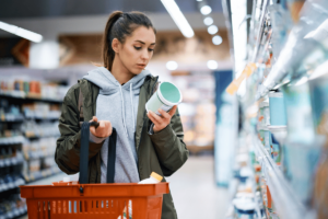 A blog image showing a young woman in a grocery store looking at a food label